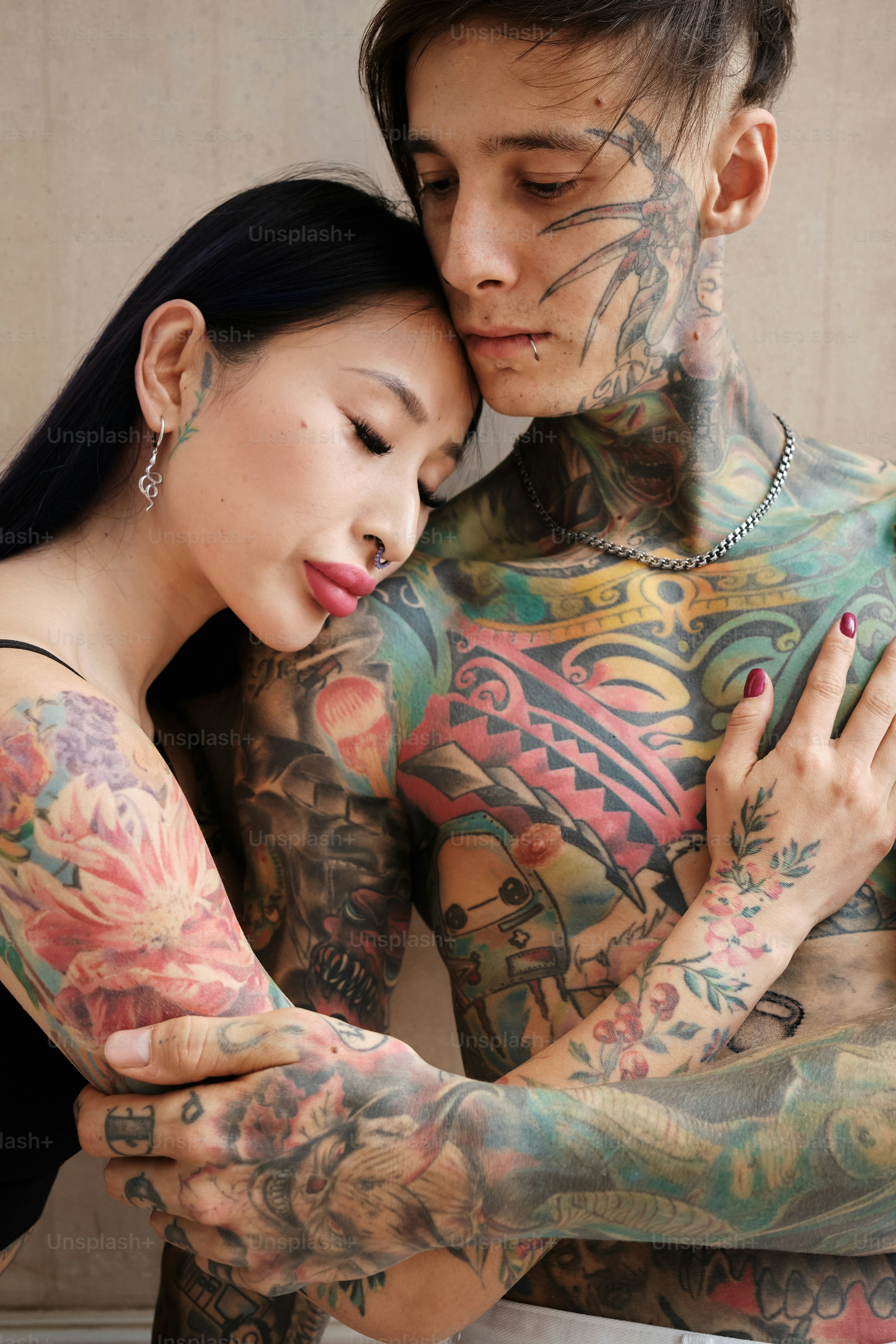 A couple of tattooed people standing together in a gentle embrace.