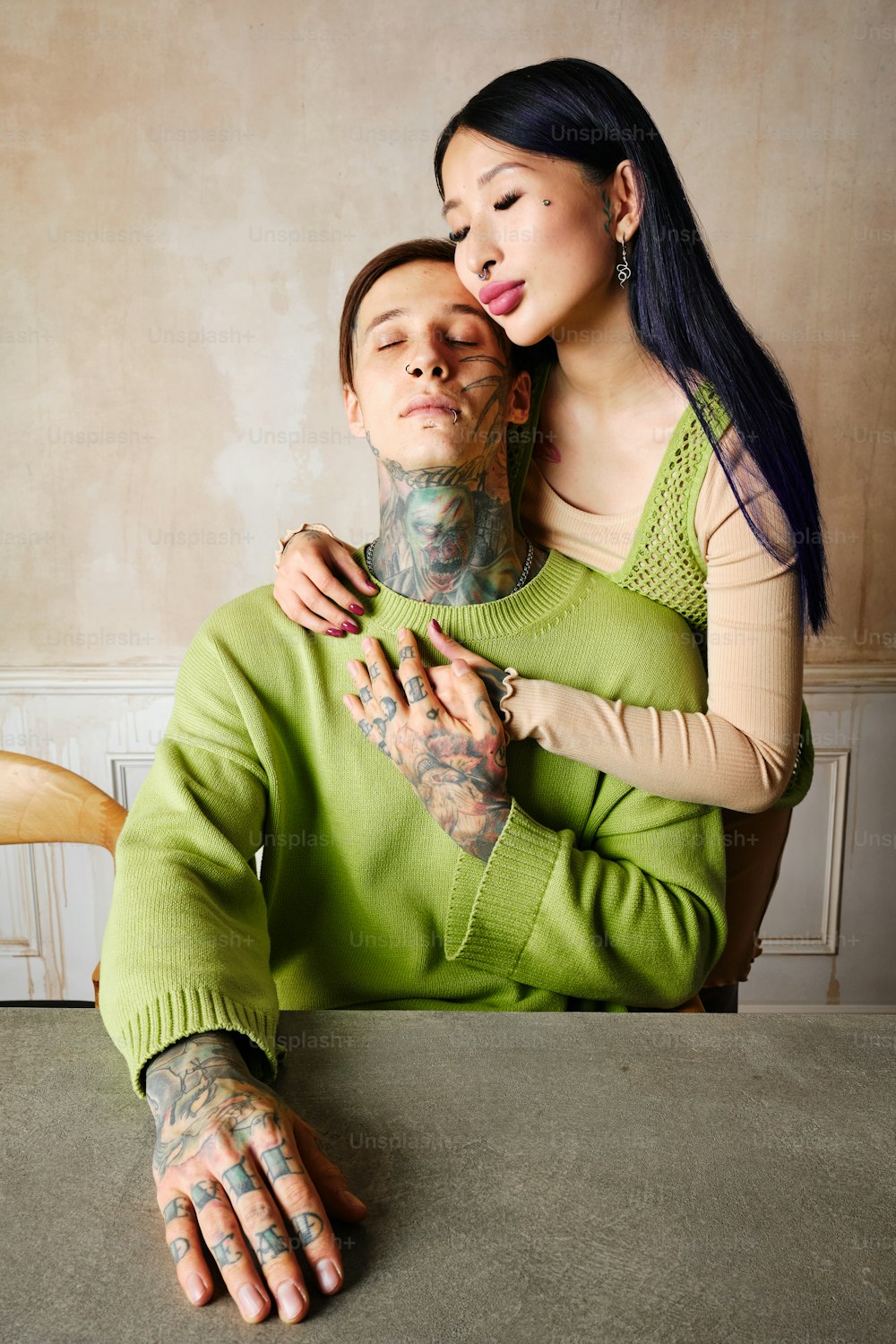 uma mulher está abraçando um homem com tatuagens em seu rosto