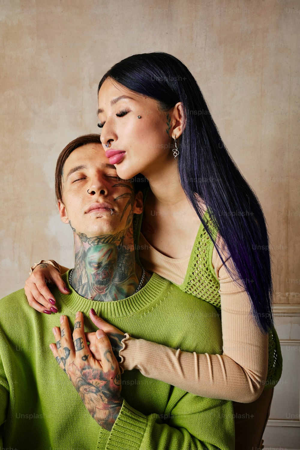 a woman is hugging a man with tattoos on his face