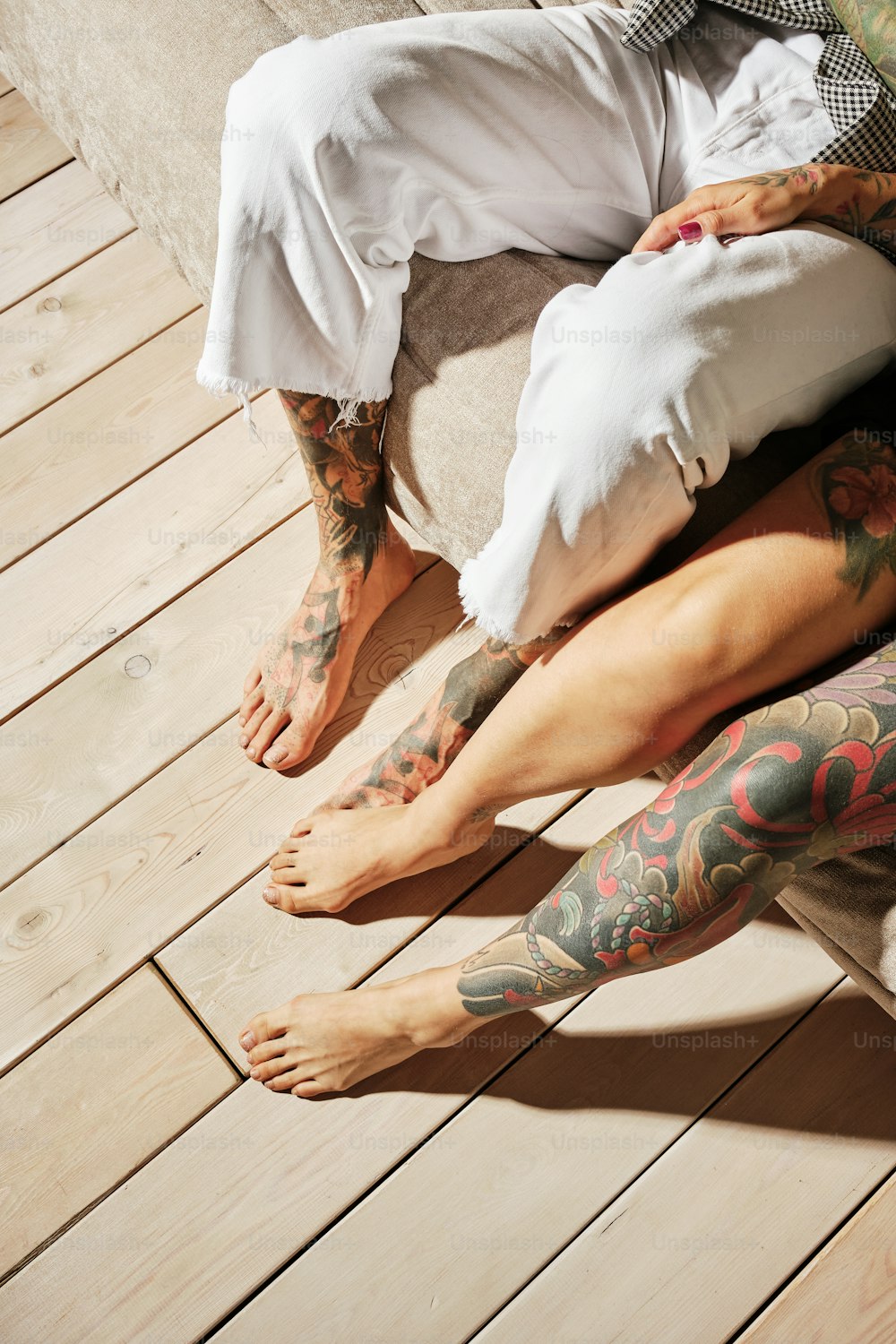 a man with tattoos sitting on a wooden floor