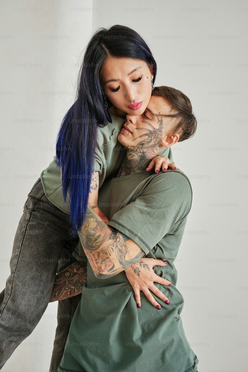 a woman is hugging a man with tattoos on his arms