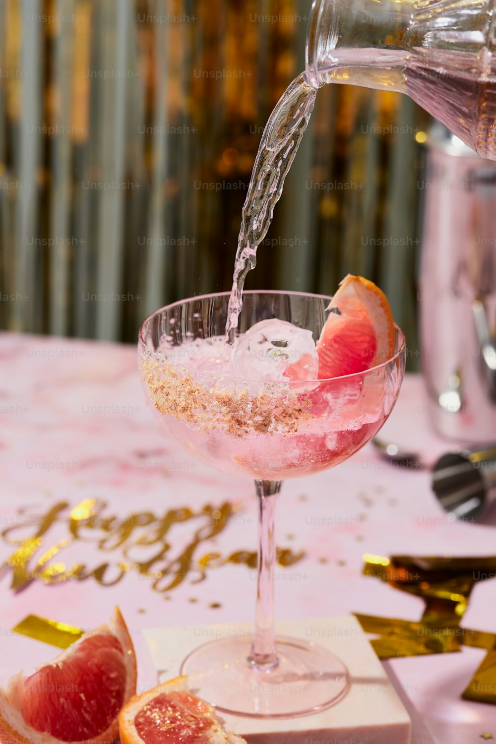 a pink cocktail being poured into a wine glass