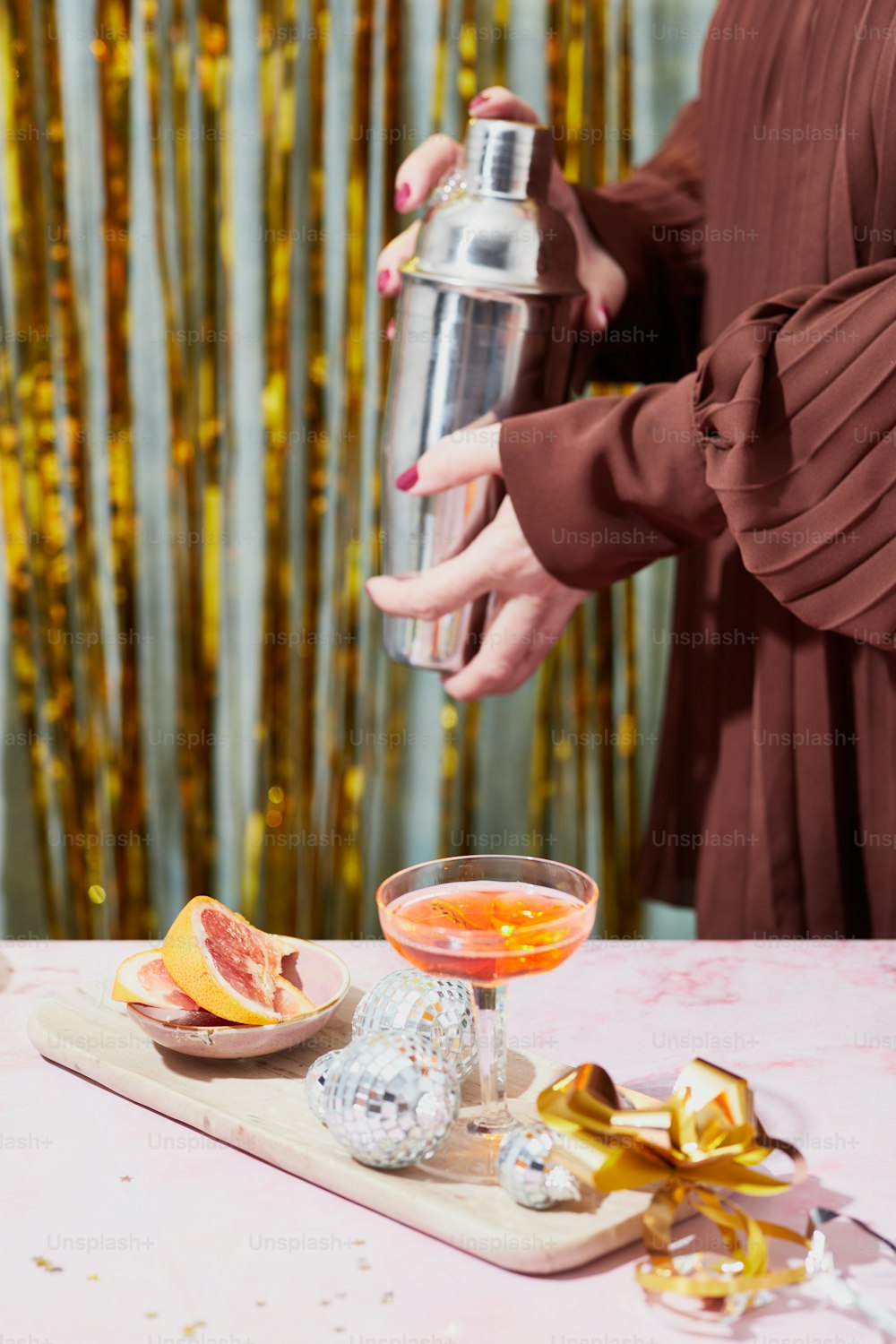 a woman in a brown dress is holding a cocktail shaker