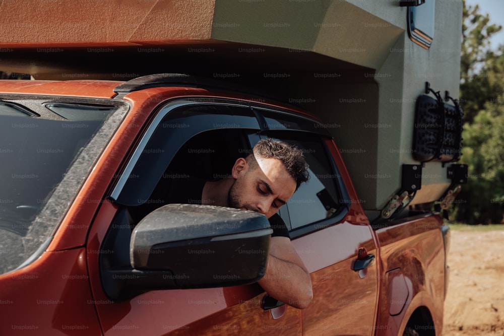 a man leaning his head out the window of a red truck