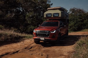 a red truck with a camper on top of it driving down a dirt road