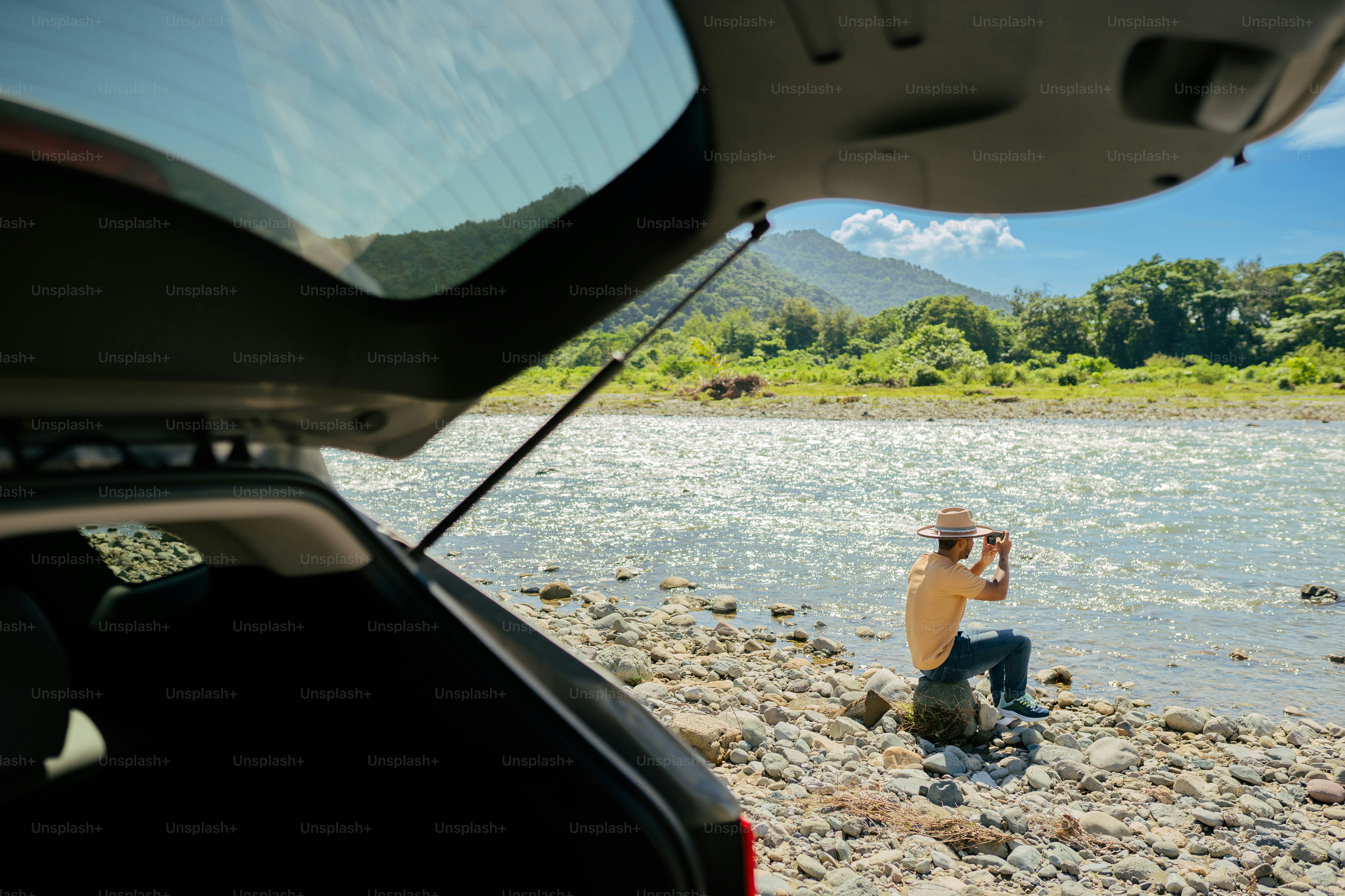 a man sitting on a rock next to a body of water