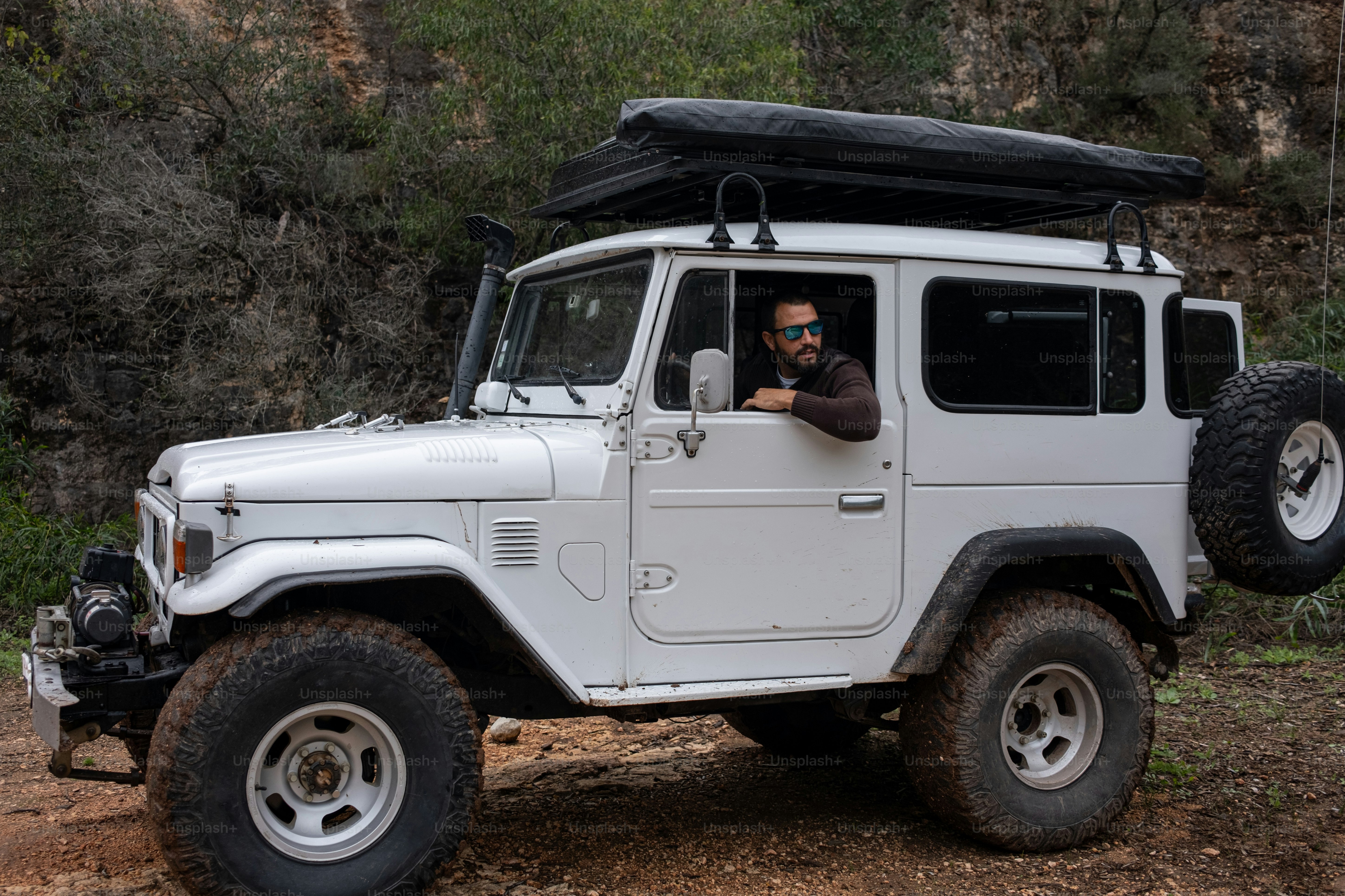 비포장 도로에서 흰색 지프를 운전하는 남자