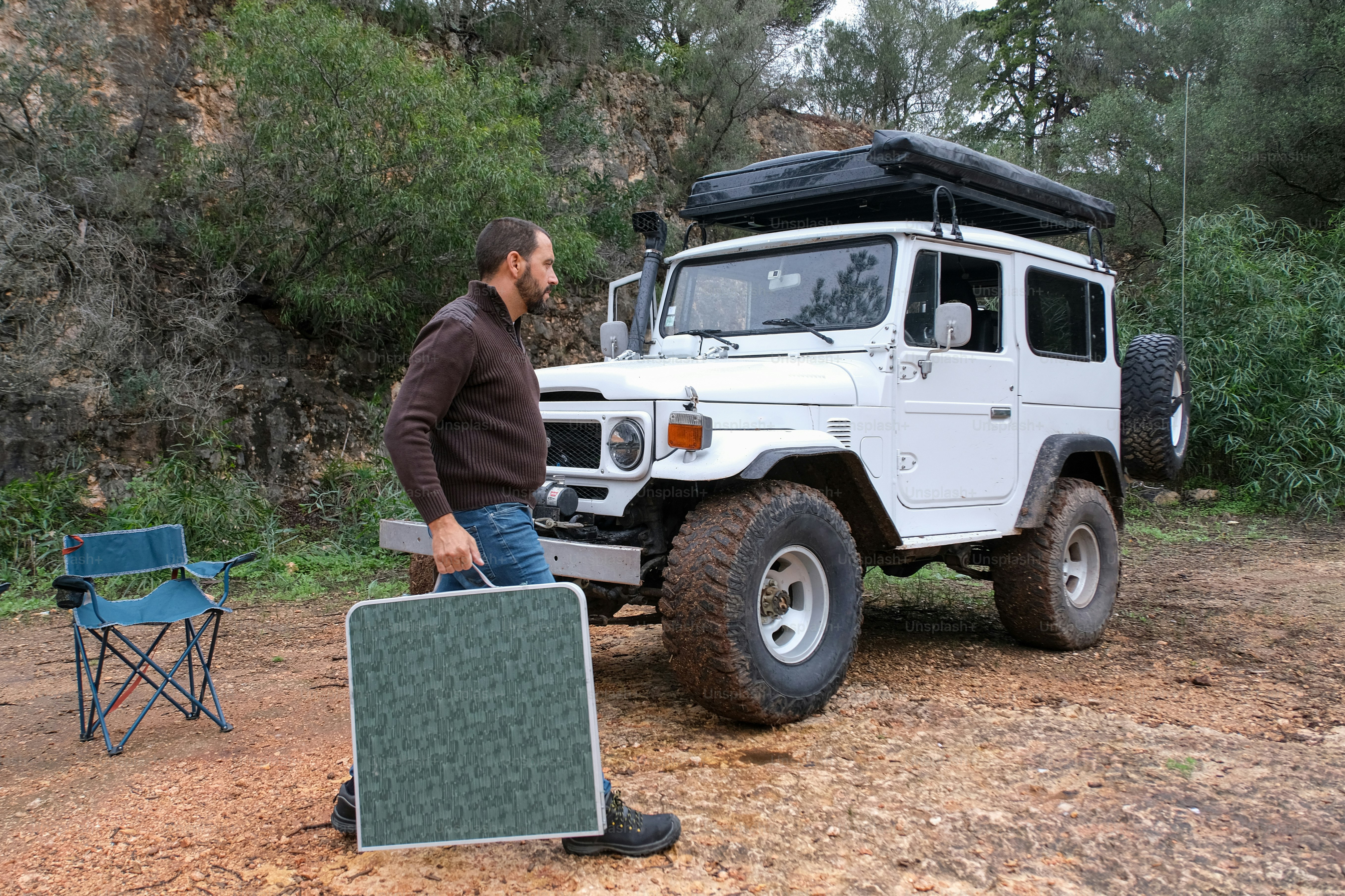Camper using solar power banks beside a tent during a remote wilderness camping trip