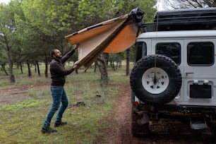 a man putting a tent on top of a vehicle