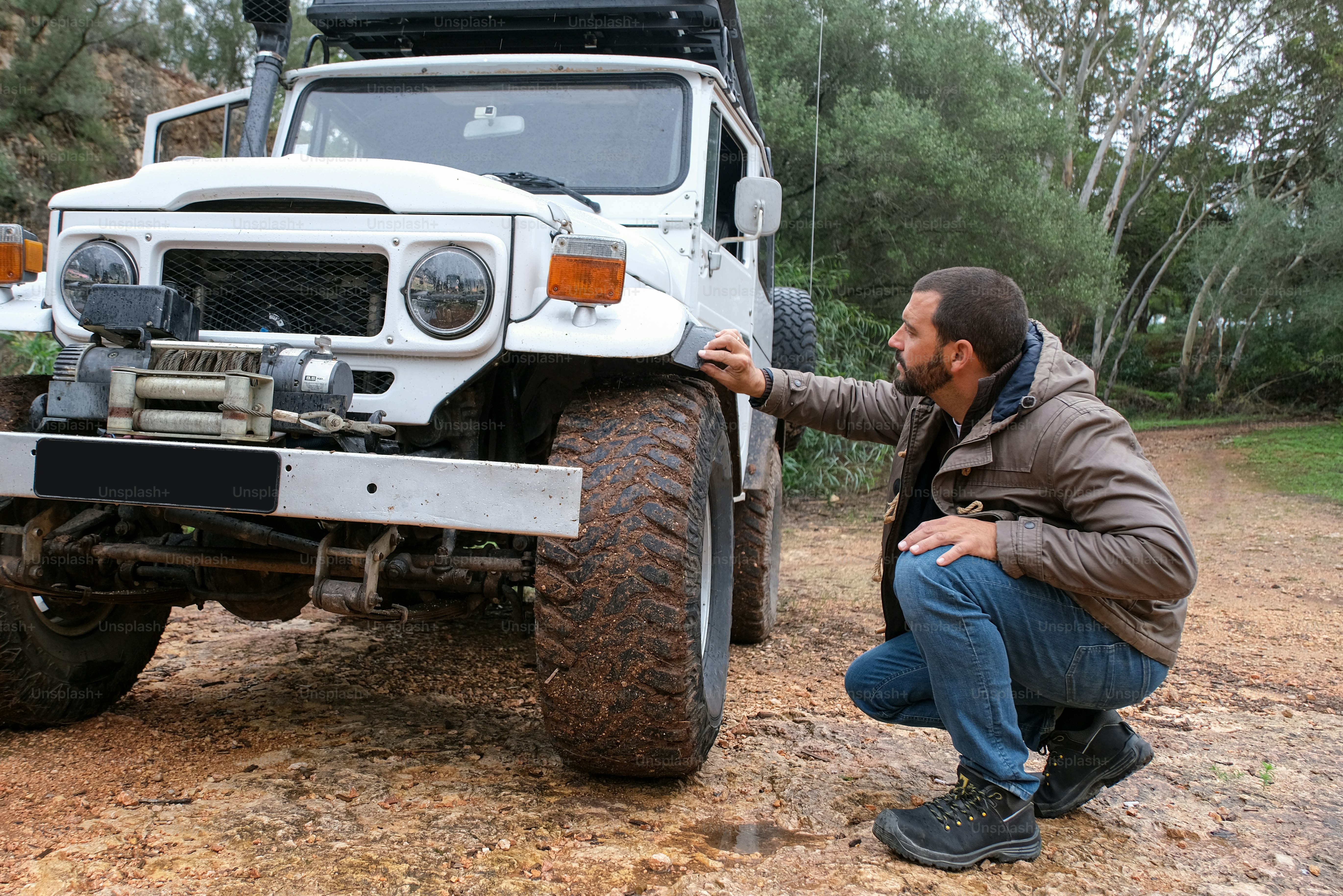 a man kneeling down next to a white truck