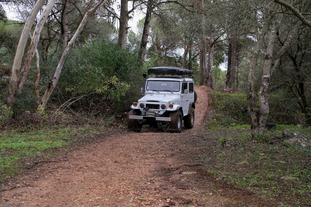 a jeep is parked on a dirt road in the woods