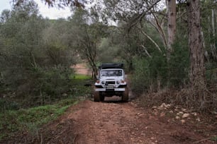 a jeep driving down a dirt road in the woods