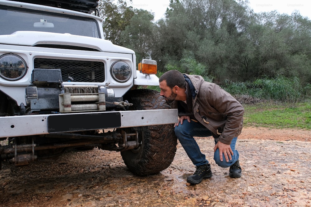 a man bending over to look at the front bumper of a truck