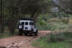 a white jeep driving down a dirt road