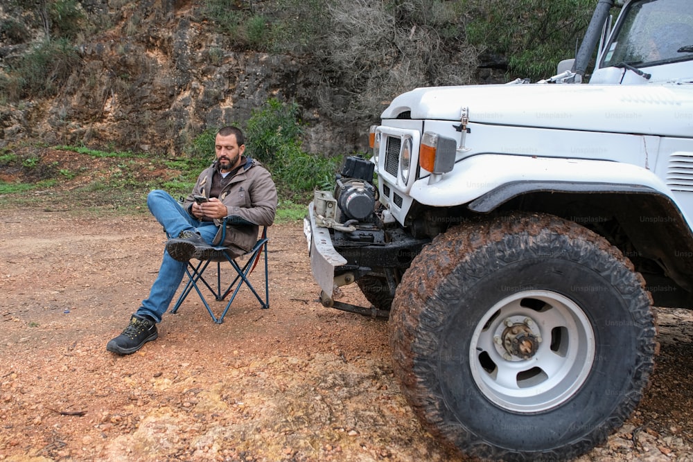 a man sitting in a chair next to a white truck