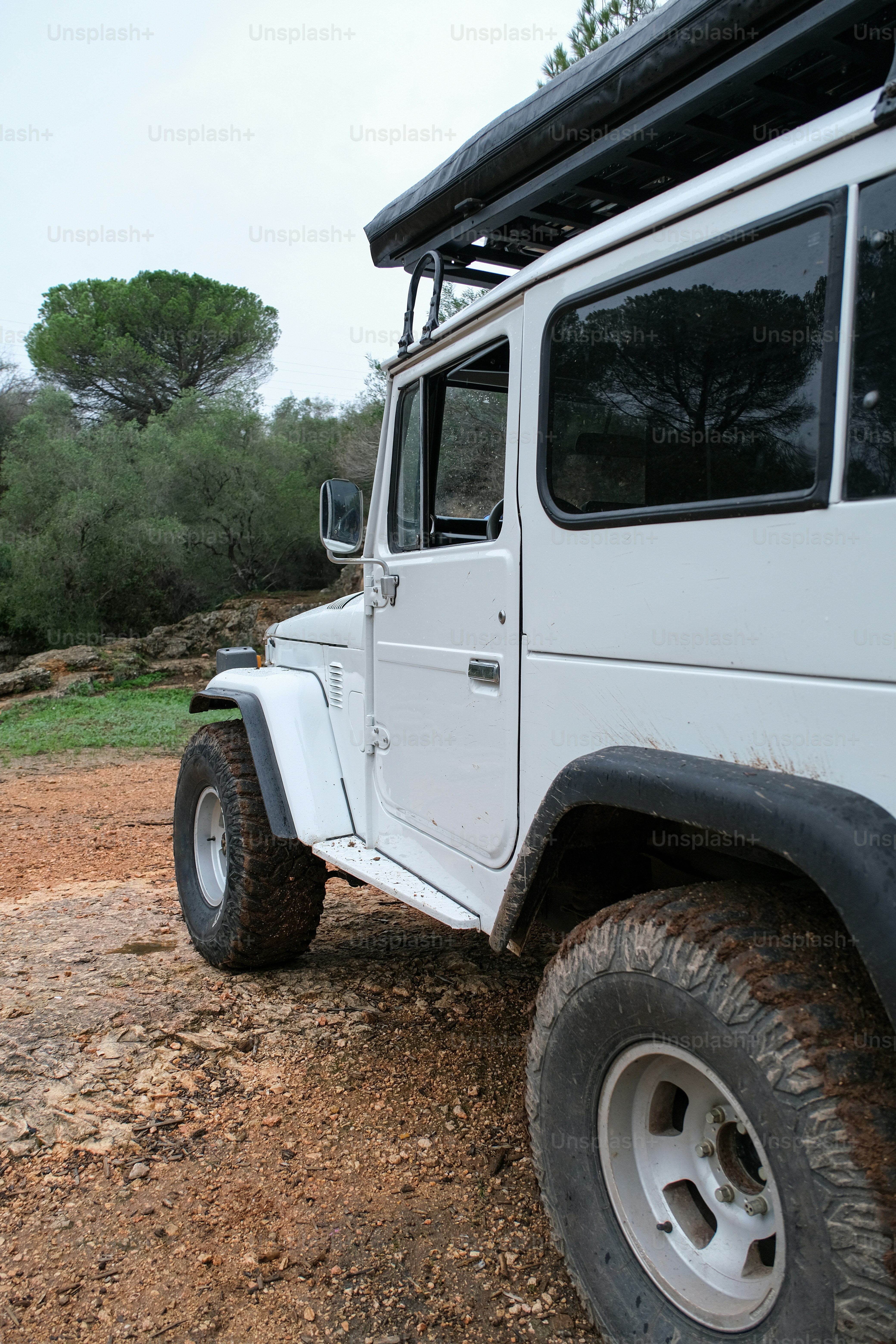 Um jipe branco estacionado em cima de um campo de terra