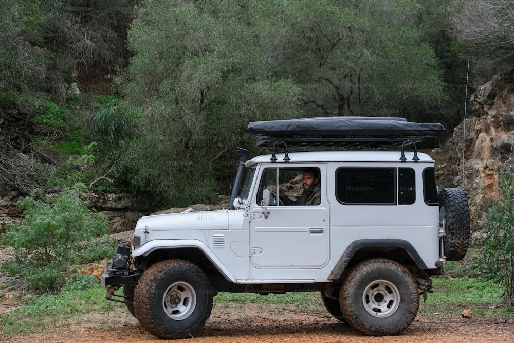 Un jeep blanco con capota negra estacionado en un camino de tierra