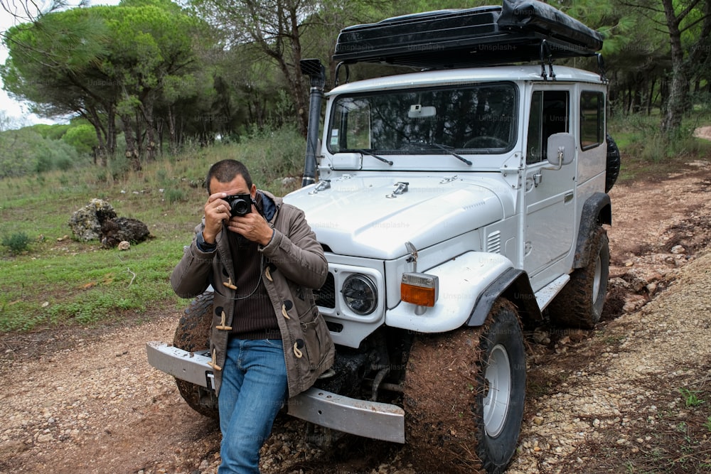 a man taking a picture of a white jeep