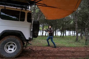 a man standing next to a white truck in a forest