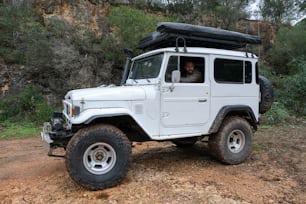 a white jeep with a black roof and a man in the driver's seat