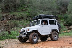 Une jeep blanche roulant sur un chemin de terre