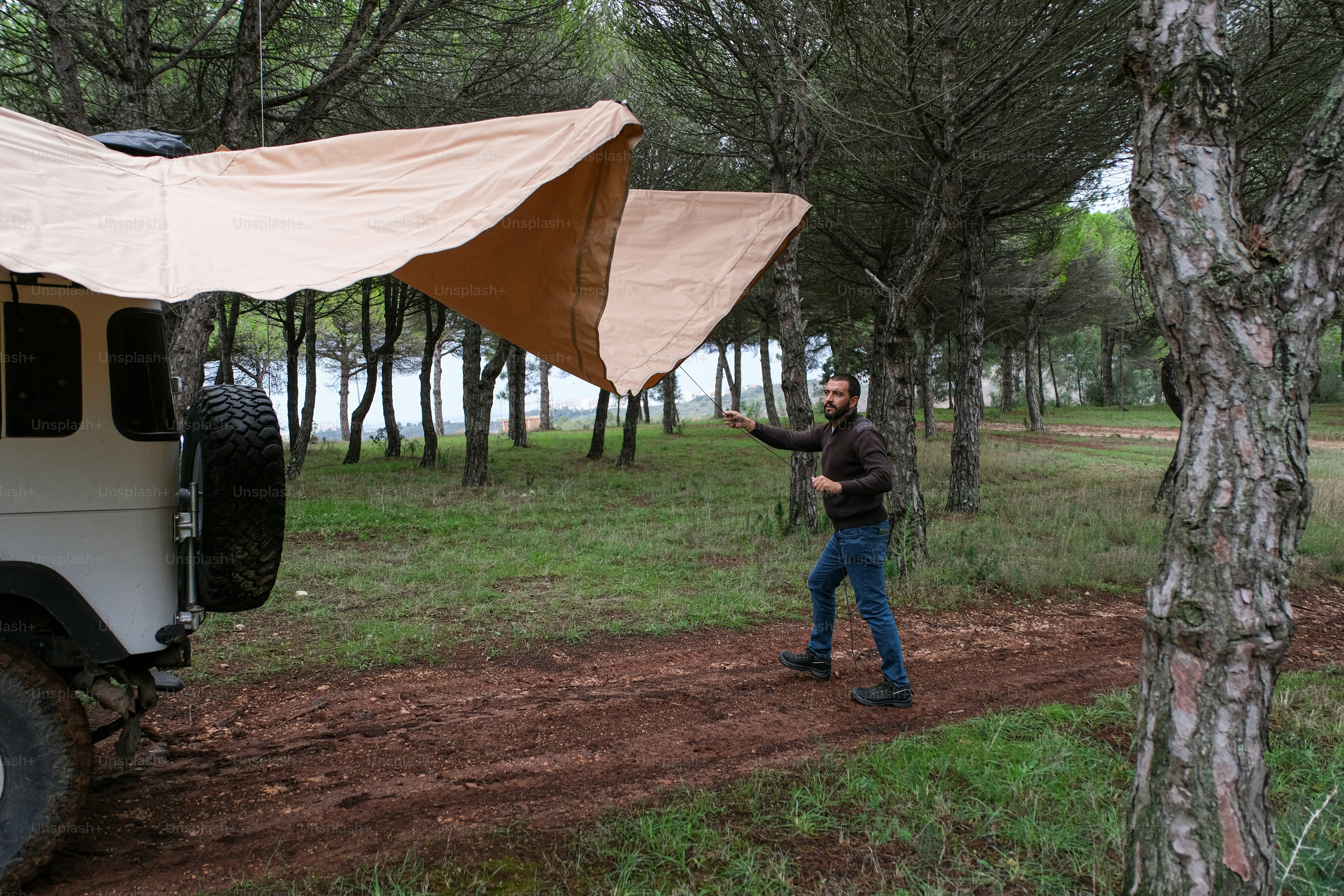 a man standing next to a white truck in a forest