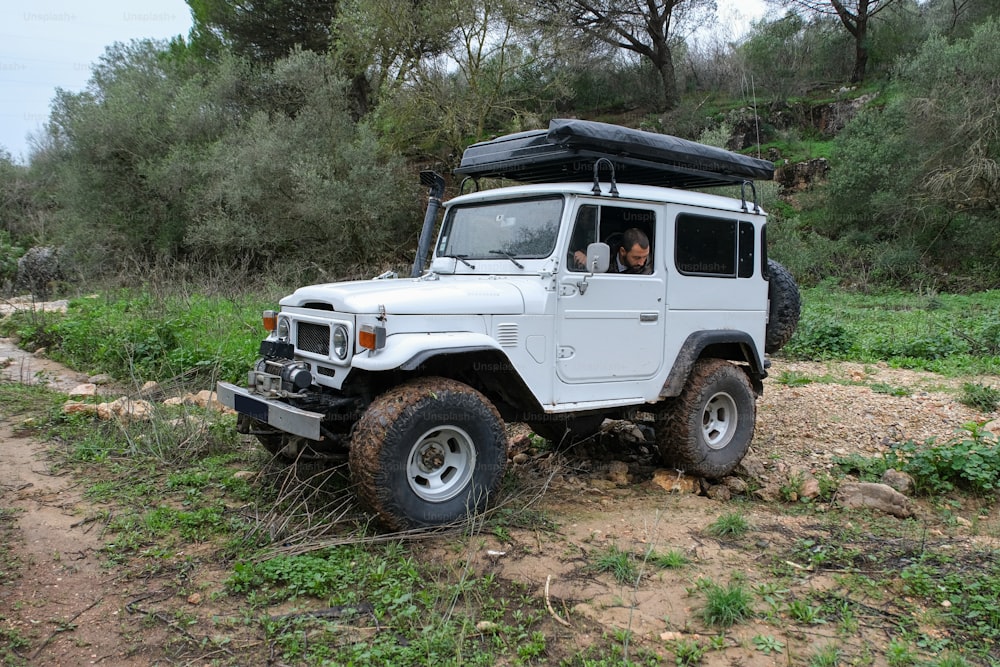 Une jeep blanche est garée sur un chemin de terre