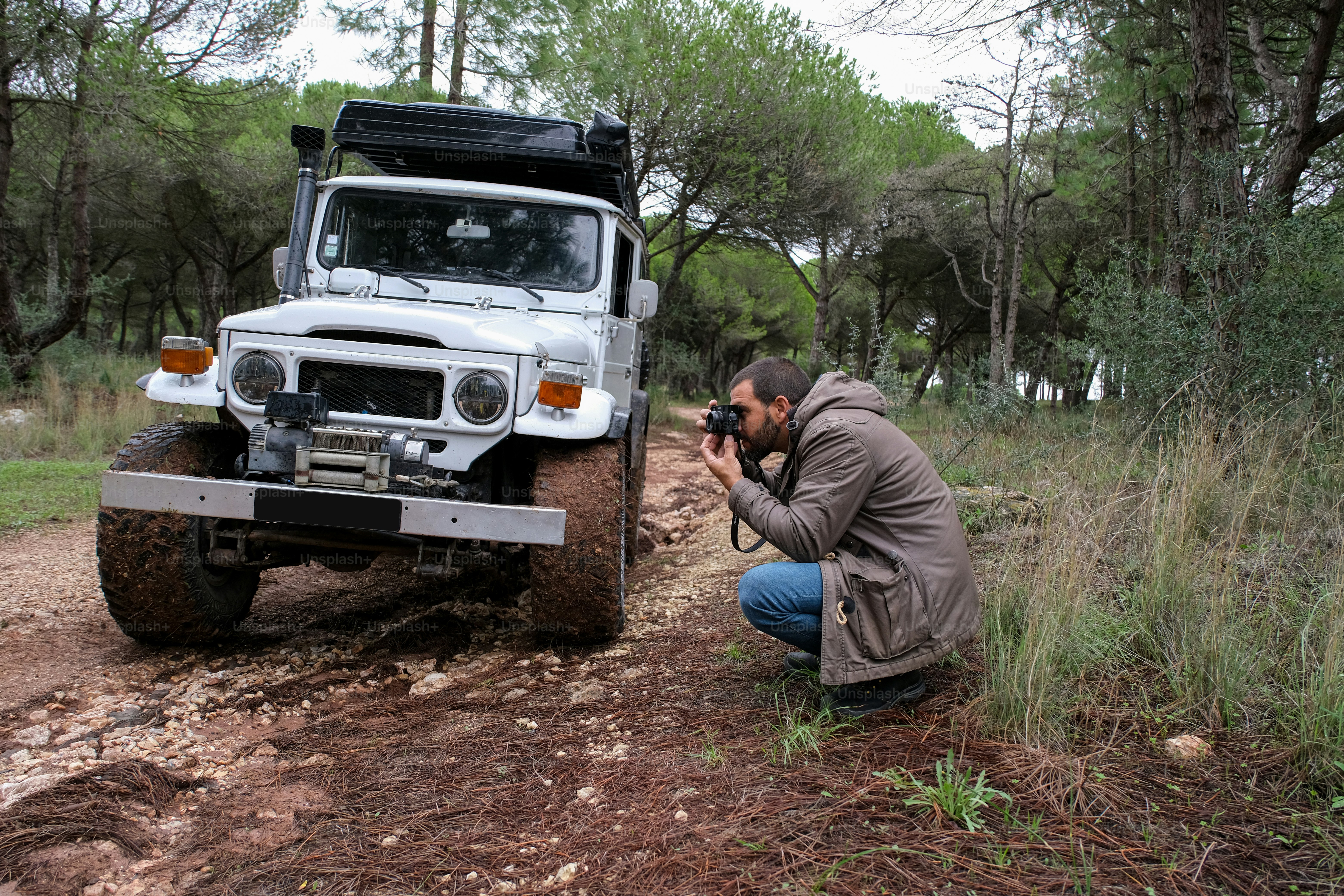 a man squatting down to take a picture of a jeep
