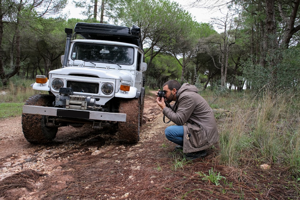 a man squatting down to take a picture of a jeep