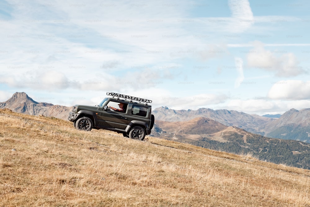 a jeep driving up a hill with mountains in the background