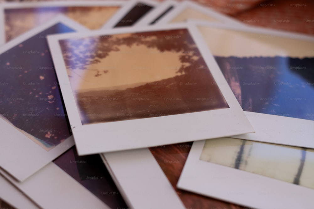 a pile of polaroid pictures sitting on top of a wooden table