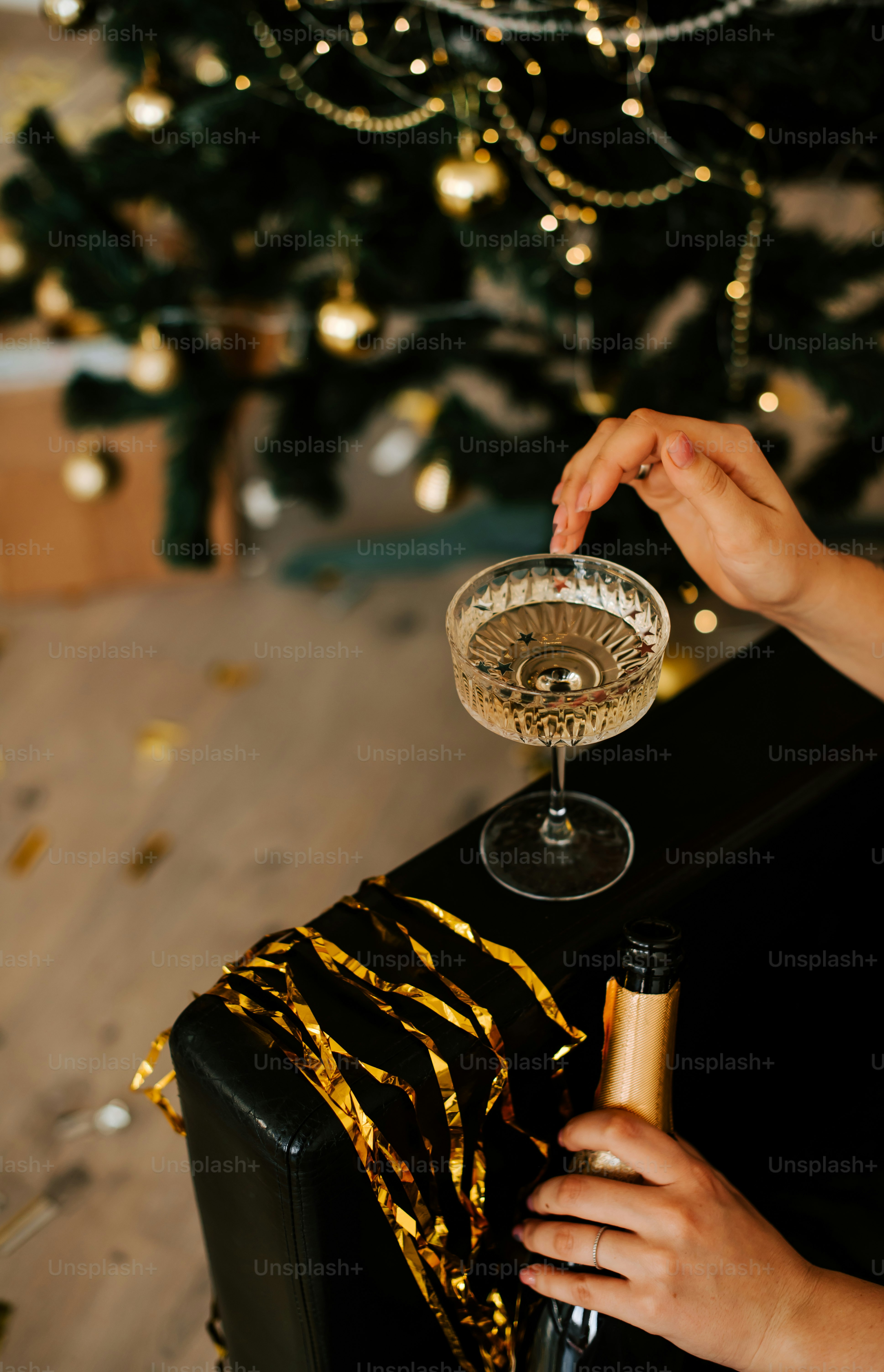 Une personne tenant un verre de vin devant un arbre de Noël