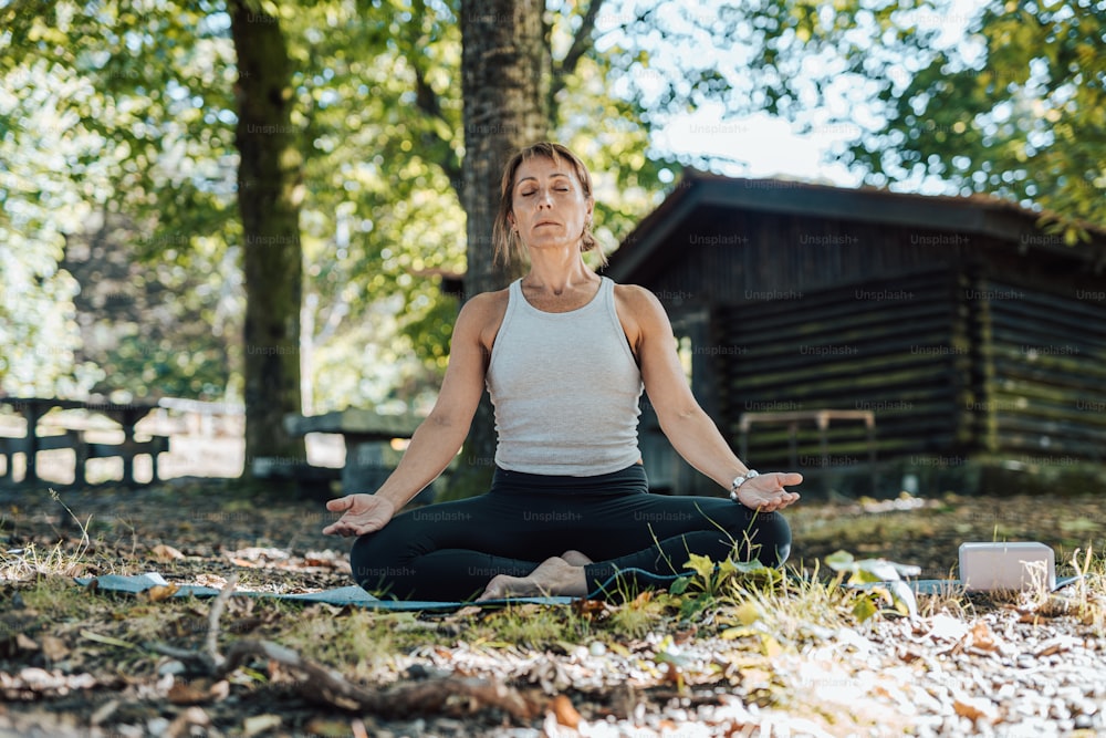 a woman in a white tank top is doing yoga