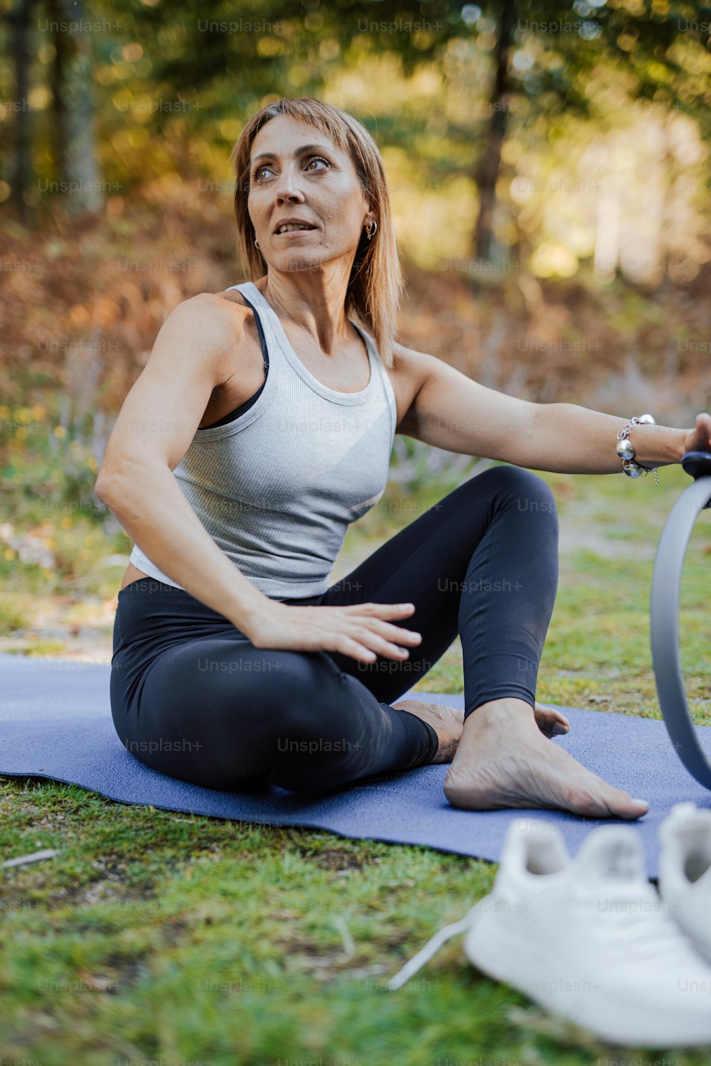 a woman sitting on a yoga mat with her hands on her hips