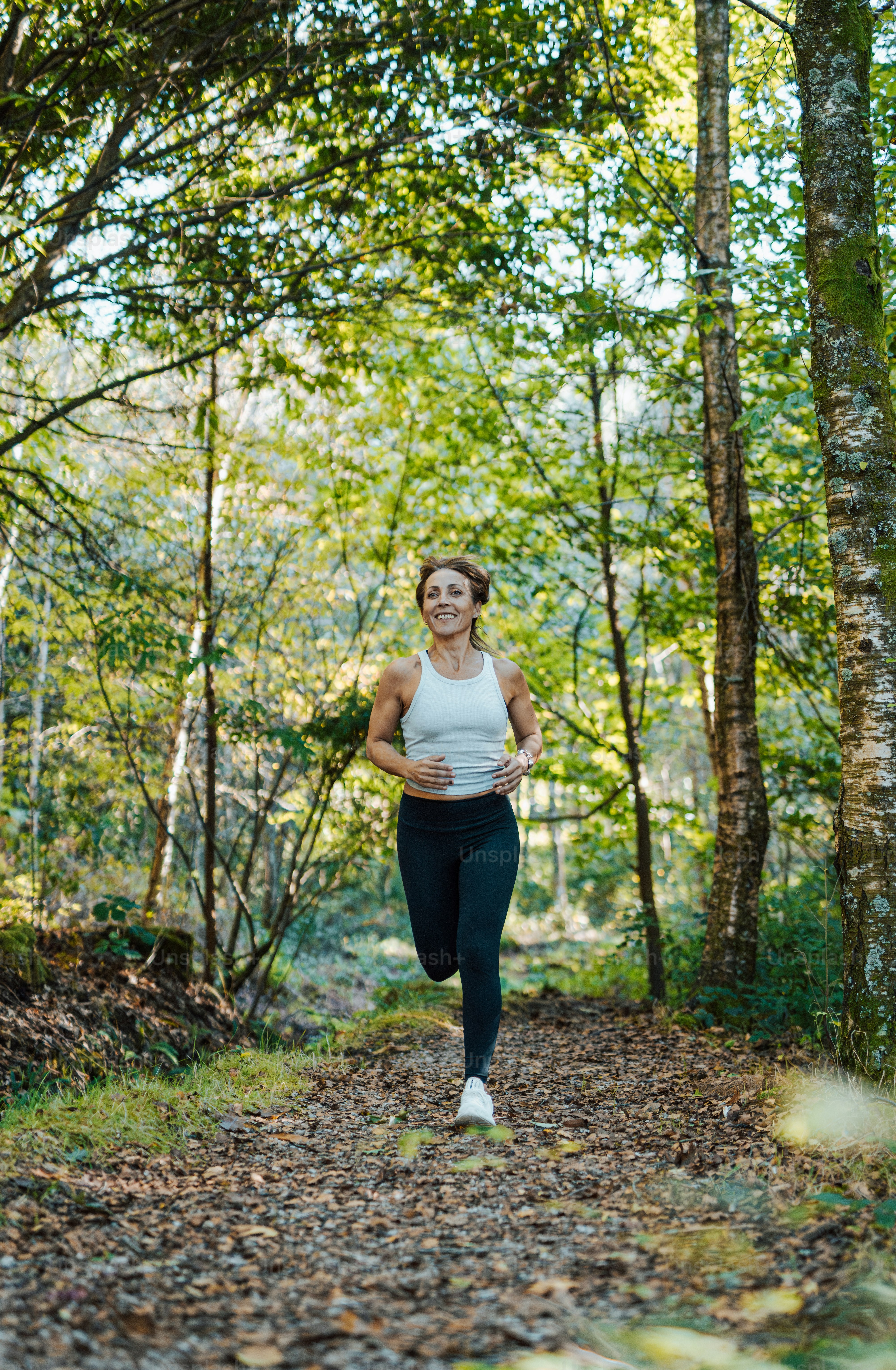 uma mulher correndo na floresta em uma trilha