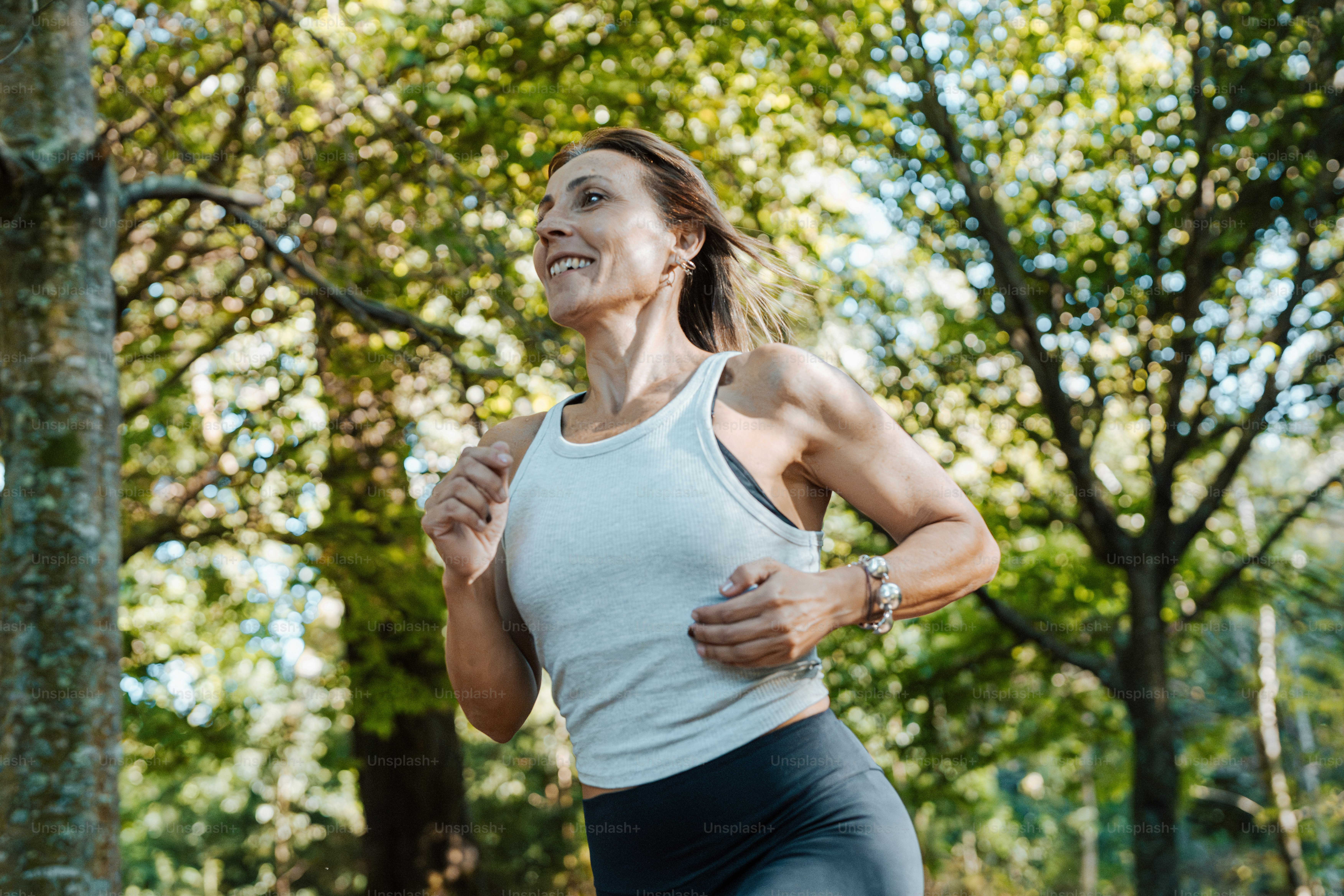 una mujer corriendo en un parque con árboles en el fondo