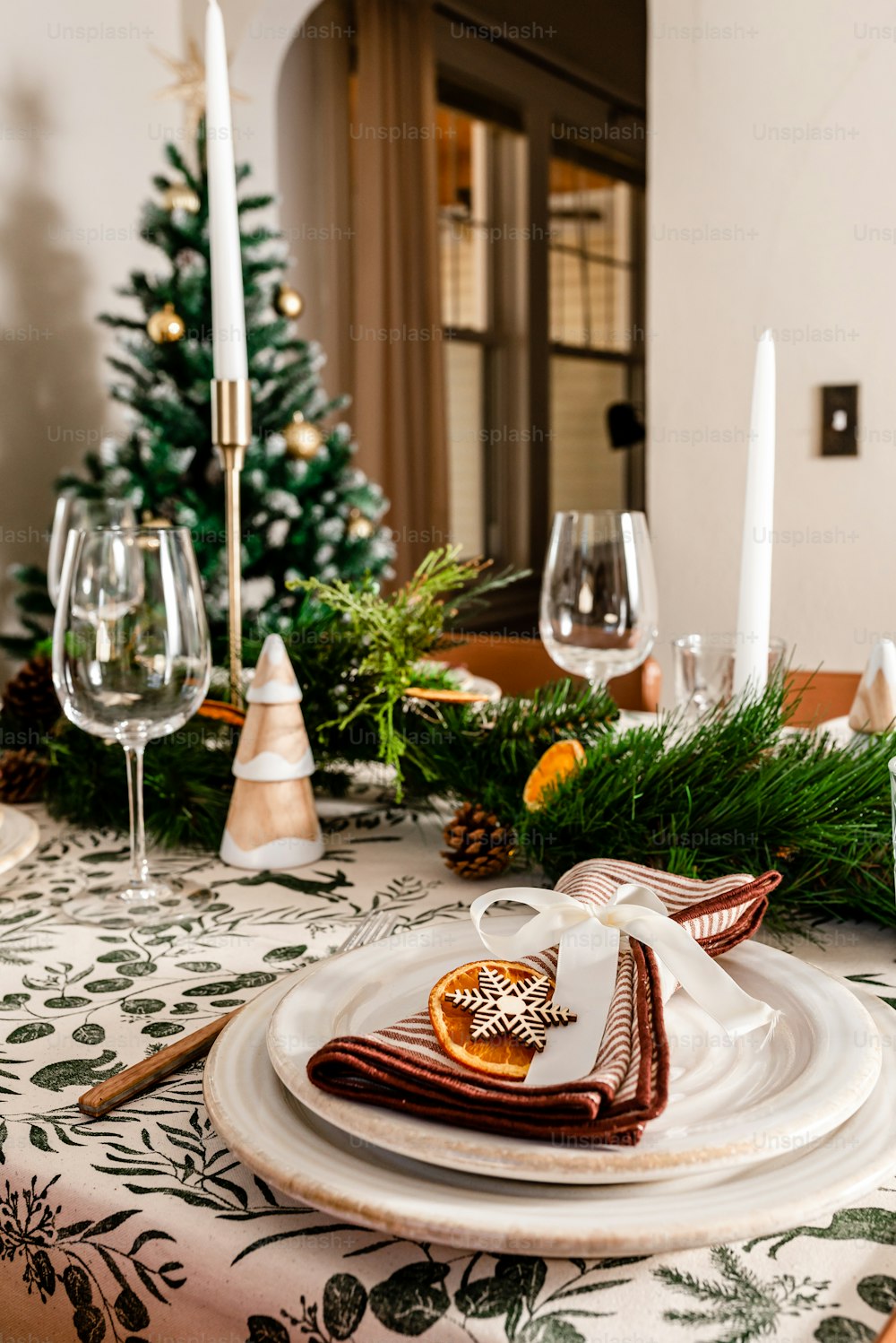 a table set for christmas with a christmas tree in the background