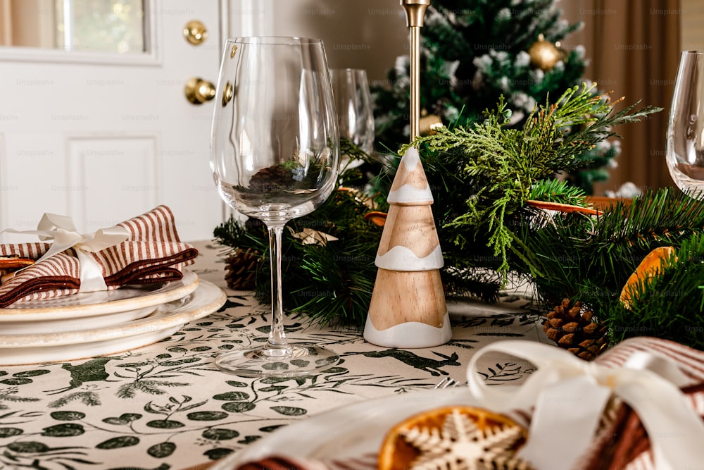 a table set for christmas with wine glasses and plates