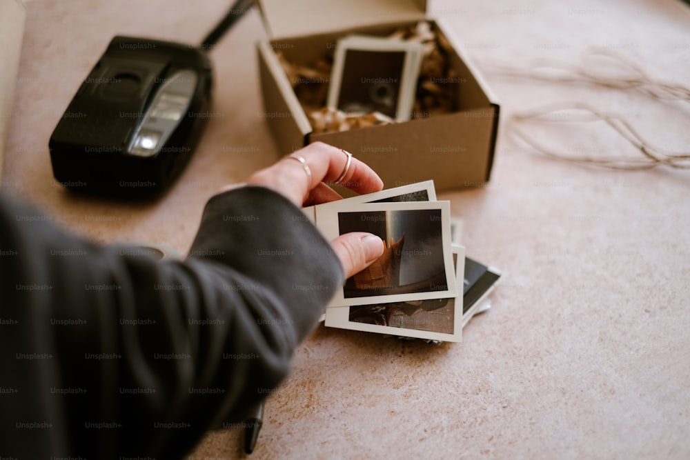 uma pessoa segurando uma caixa de fotos em uma mesa