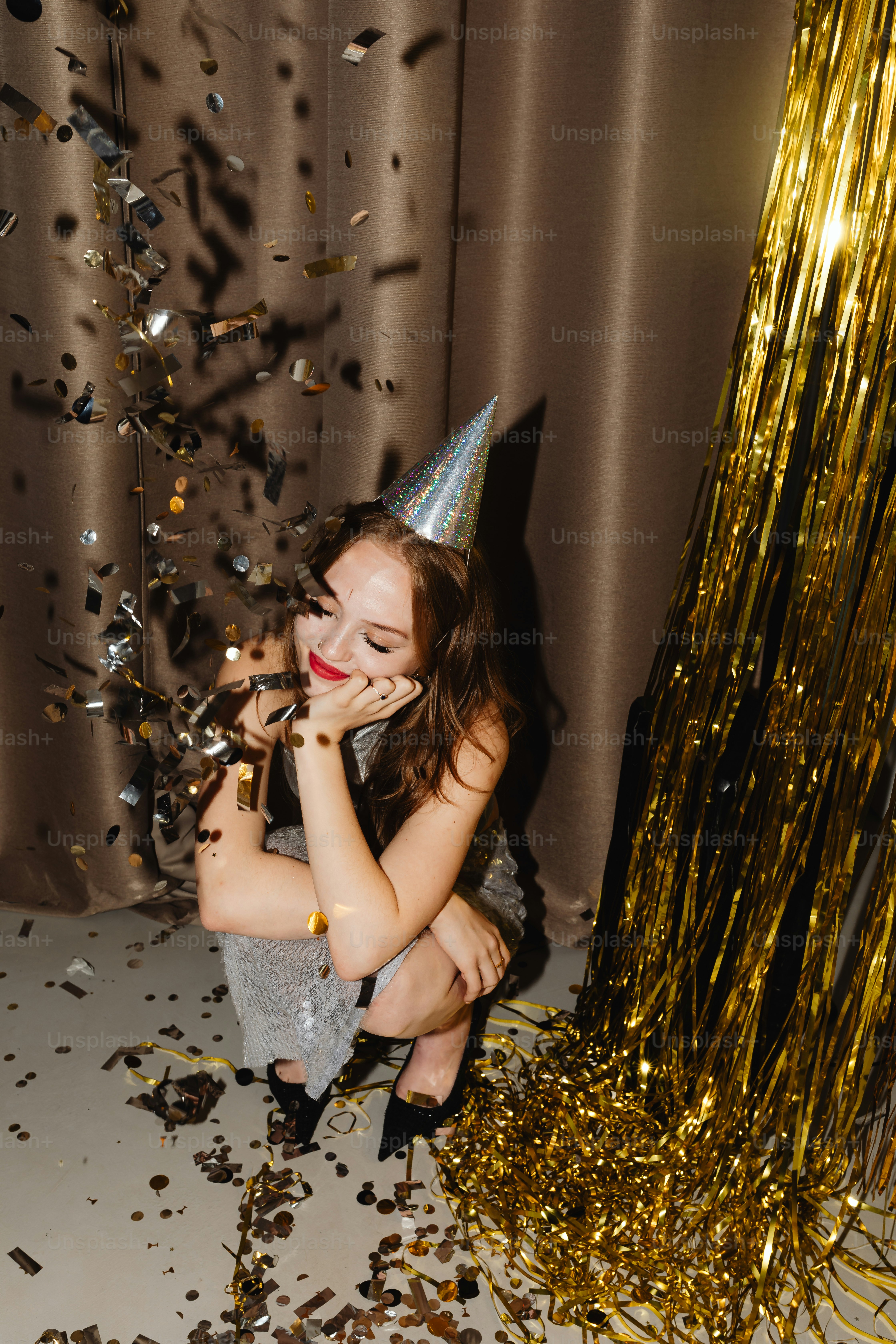 a little girl sitting on the floor with a party hat on