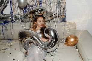 a woman sitting on a couch with balloons