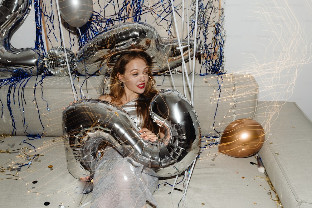 eine Frau, die mit Luftballons auf einer Couch sitzt