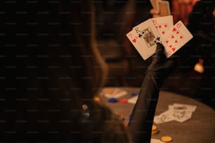 a person holding up playing cards on a table