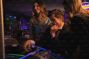 a group of people standing around a pinball machine
