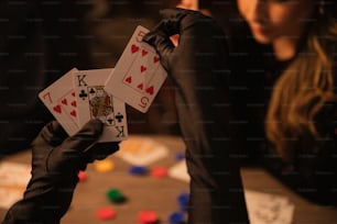 a person holding up two playing cards on a table