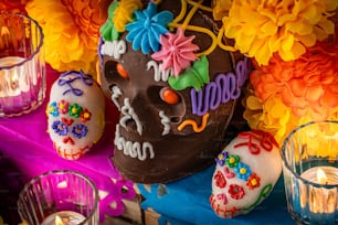 Una calavera de chocolate decorada rodeada de velas y flores