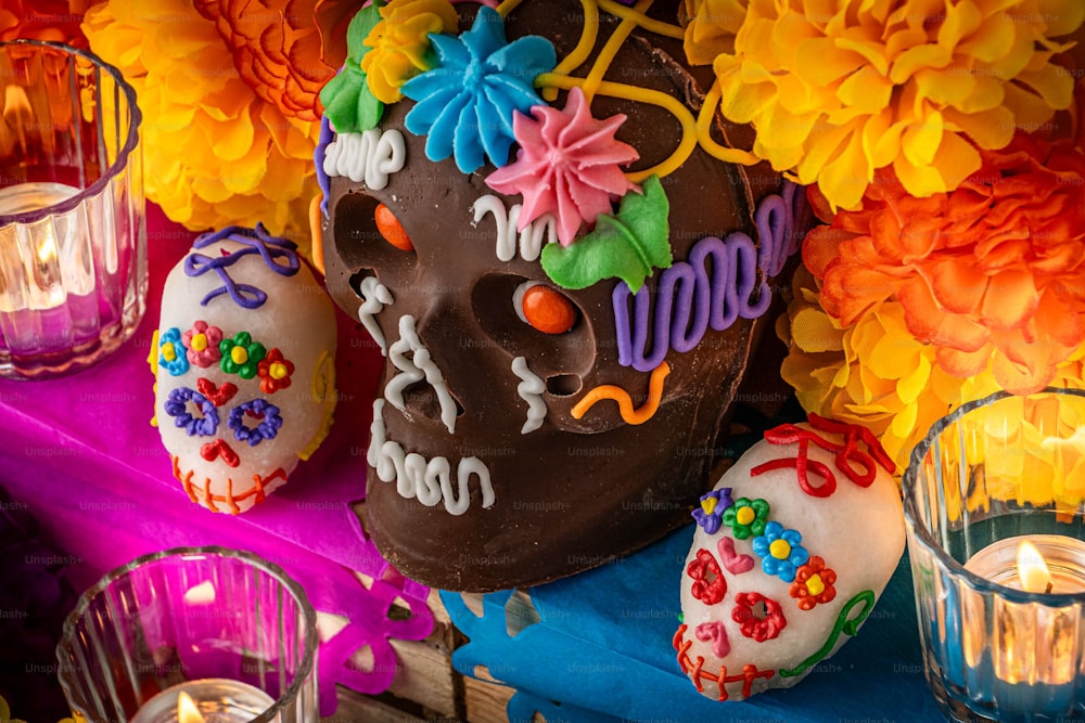 un crâne en chocolat décoré entouré de bougies et de fleurs