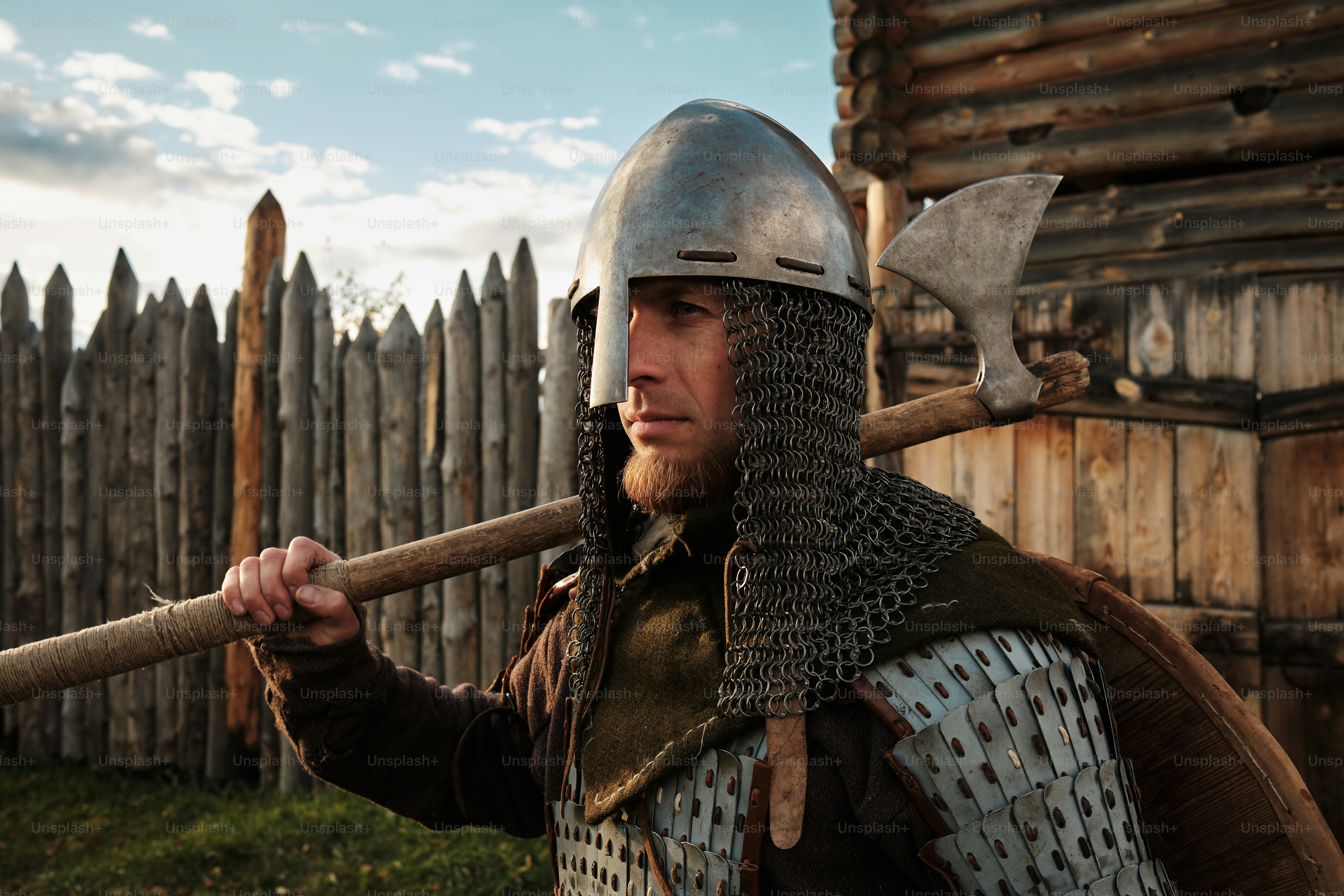 a man dressed in armor holding a wooden stick