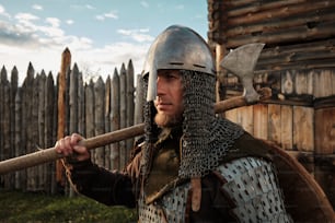 a man dressed in armor holding a wooden stick