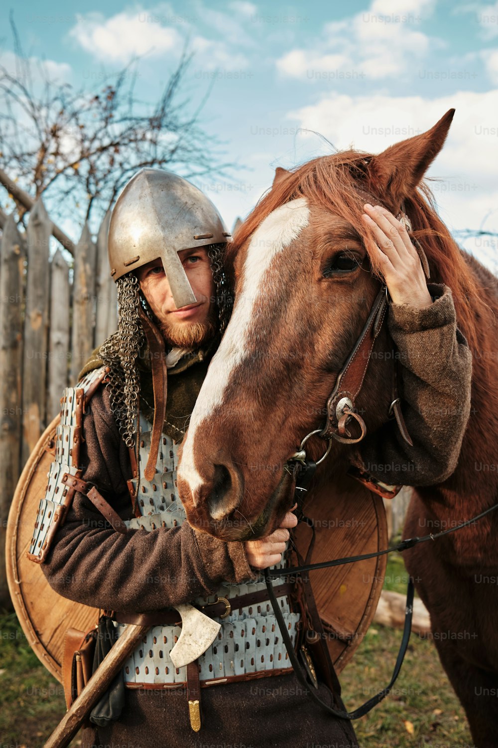 Un hombre con casco está de pie junto a un caballo